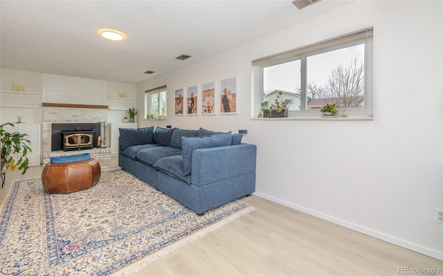 living room featuring a textured ceiling, wood finished floors, visible vents, and baseboards