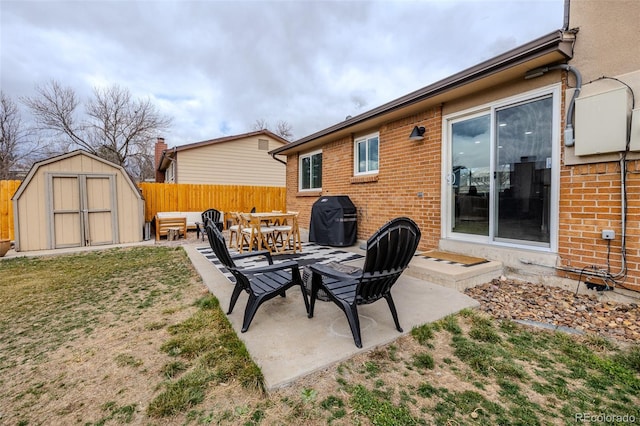 view of patio featuring a storage shed, a grill, fence, and an outbuilding