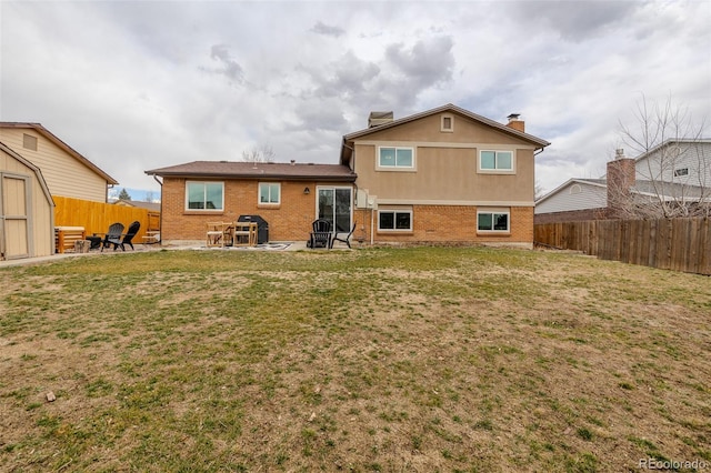 rear view of property with a patio area, brick siding, a yard, and a fenced backyard