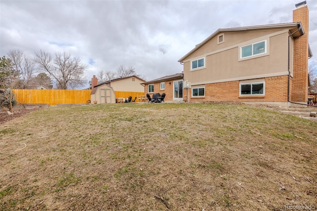 rear view of property with brick siding, a yard, fence, a shed, and an outdoor structure