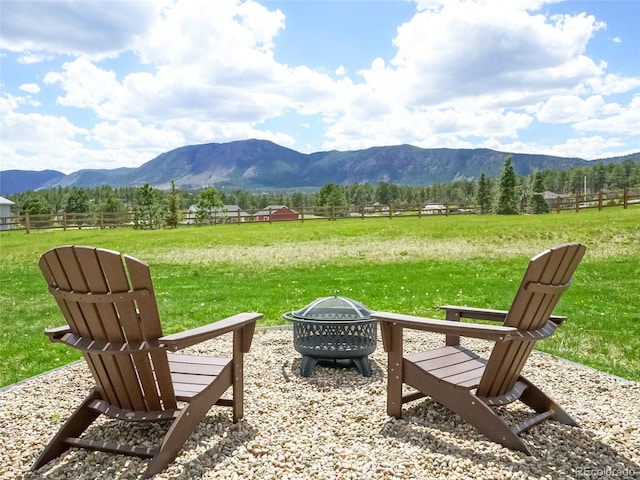exterior space featuring fence, a mountain view, a fire pit, and a rural view