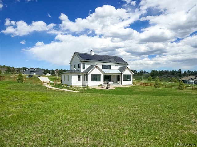 back of property featuring fence, roof mounted solar panels, a patio area, a lawn, and metal roof