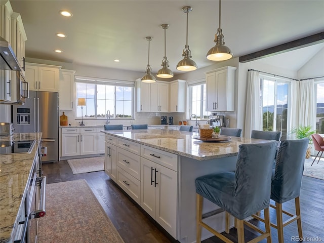kitchen with a healthy amount of sunlight, a breakfast bar area, recessed lighting, and dark wood finished floors
