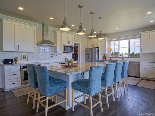 kitchen featuring white cabinets, dark wood-style flooring, appliances with stainless steel finishes, wall chimney exhaust hood, and recessed lighting