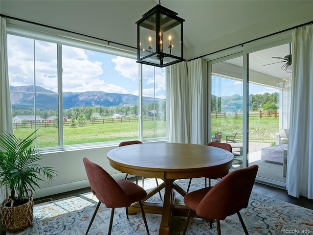 dining room with visible vents, a mountain view, wood finished floors, and ceiling fan with notable chandelier
