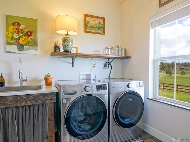 laundry area featuring washing machine and clothes dryer, laundry area, a sink, baseboards, and wood finished floors