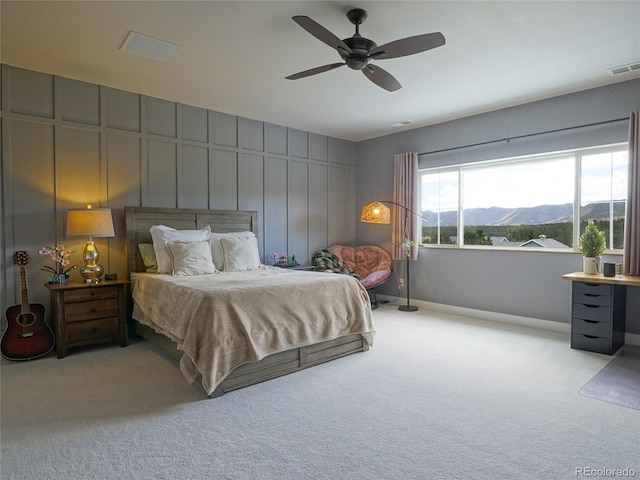 carpeted bedroom featuring visible vents, a ceiling fan, a mountain view, and baseboards