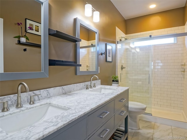 bathroom with double vanity, a sink, a stall shower, and toilet