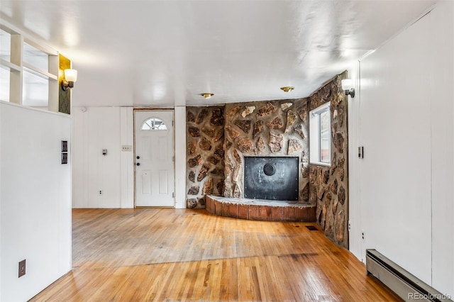 unfurnished living room with hardwood / wood-style floors and a baseboard heating unit