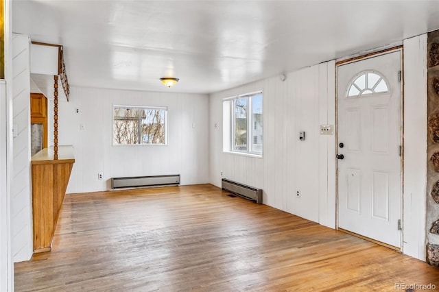 foyer with light wood-type flooring and a baseboard heating unit