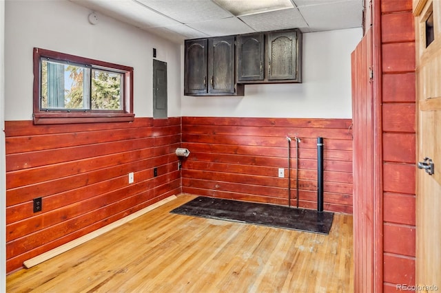 clothes washing area with hardwood / wood-style flooring and wooden walls