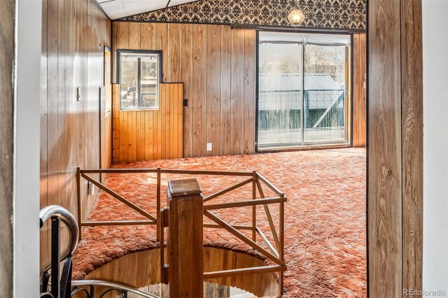 corridor with lofted ceiling and wood walls