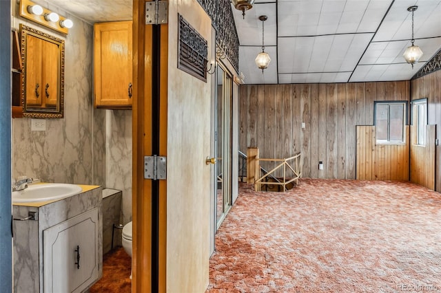 bathroom featuring wood walls, vanity, and toilet