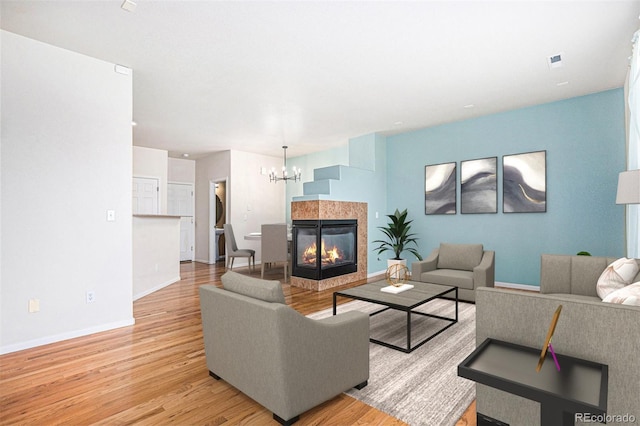 12710 Jasmine St Unit C, Thornton, CO 80602 - living area featuring baseboards, light wood finished floors, a tiled fireplace, and a notable chandelier