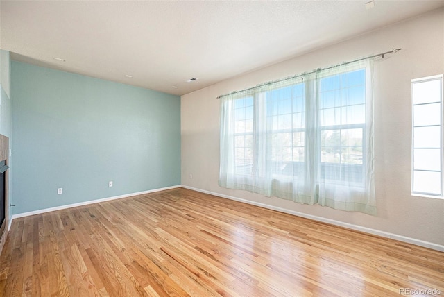 12710 Jasmine St Unit C, Thornton, CO 80602 - unfurnished living room featuring baseboards, a glass covered fireplace, and wood finished floors