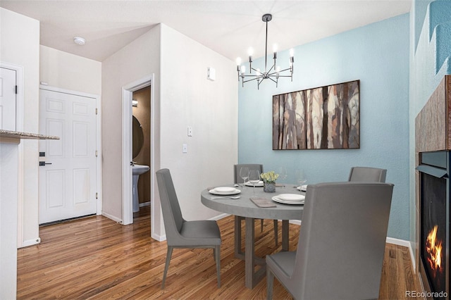 12710 Jasmine St Unit C, Thornton, CO 80602 - dining area featuring baseboards, a warm lit fireplace, wood finished floors, and a chandelier