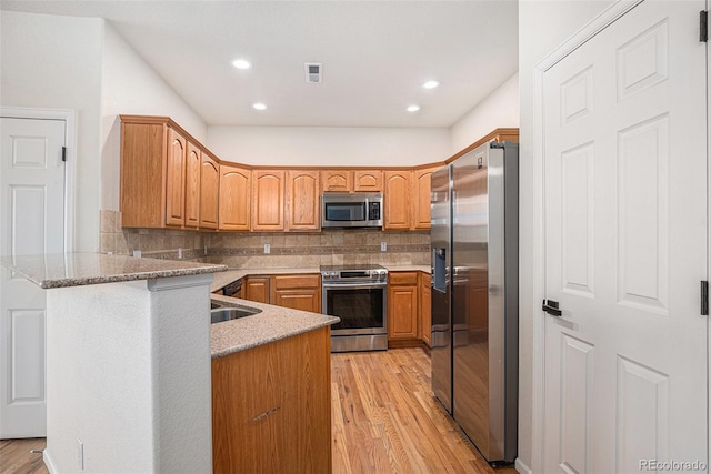 12710 Jasmine St Unit C, Thornton, CO 80602 - kitchen with visible vents, a peninsula, light wood finished floors, backsplash, and stainless steel appliances