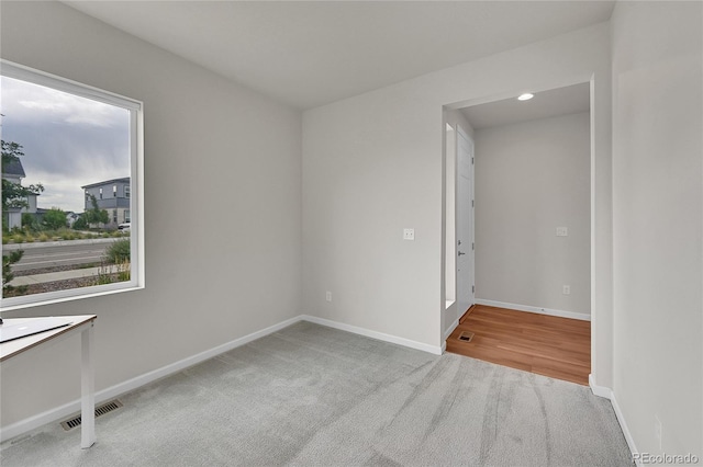 empty room featuring light colored carpet, visible vents, and baseboards