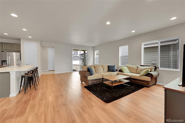 living area featuring light wood-style flooring, baseboards, and recessed lighting