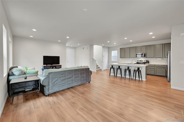 living area with stairs, light wood-type flooring, baseboards, and recessed lighting