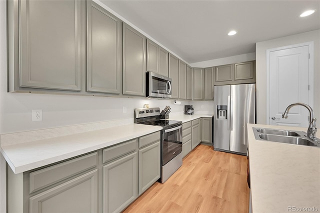 kitchen with a sink, gray cabinets, stainless steel appliances, and light countertops