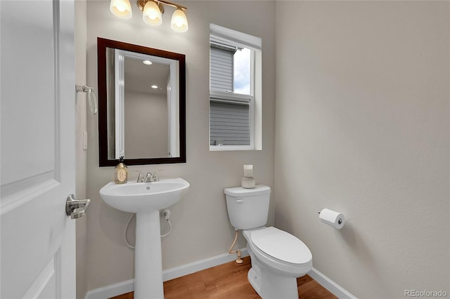 bathroom featuring a sink, wood finished floors, toilet, and baseboards