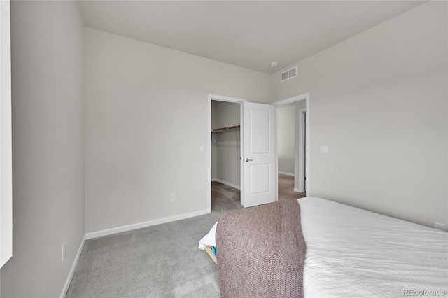 unfurnished bedroom with carpet flooring, visible vents, baseboards, a closet, and a walk in closet