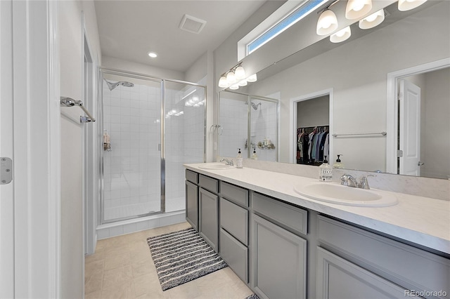 full bathroom featuring a shower stall, a spacious closet, visible vents, and a sink