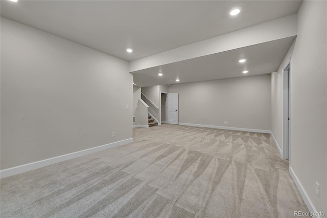 below grade area with light carpet, stairs, baseboards, and recessed lighting