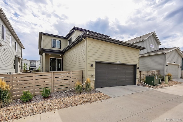 view of front of house featuring a garage, concrete driveway, central AC unit, and fence