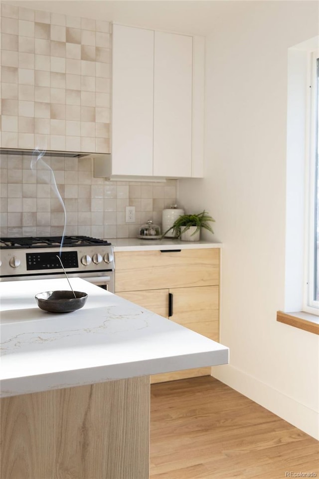 4631 Zuni St, Denver, CO 80211 - kitchen featuring stainless steel range with gas cooktop, modern cabinets, light countertops, decorative backsplash, and light wood-style floors