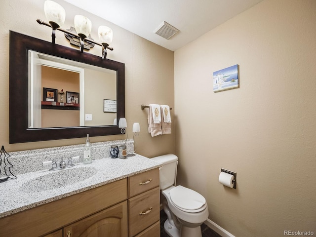 half bathroom featuring visible vents, vanity, toilet, and baseboards