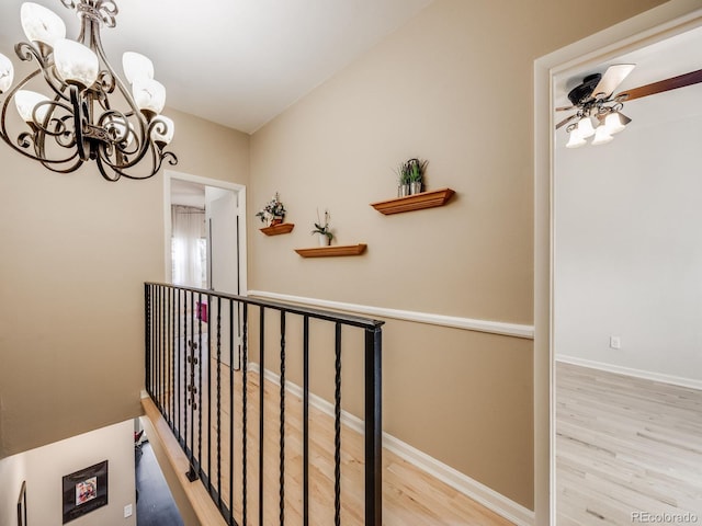 corridor featuring a chandelier, baseboards, and wood finished floors