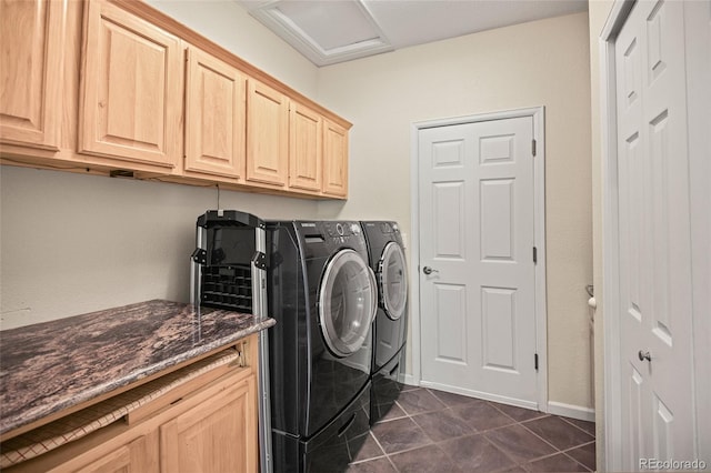 washroom with dark tile patterned floors, cabinets, and washing machine and dryer