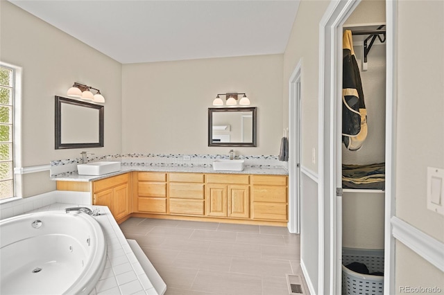 bathroom featuring tiled bath, vanity, and plenty of natural light