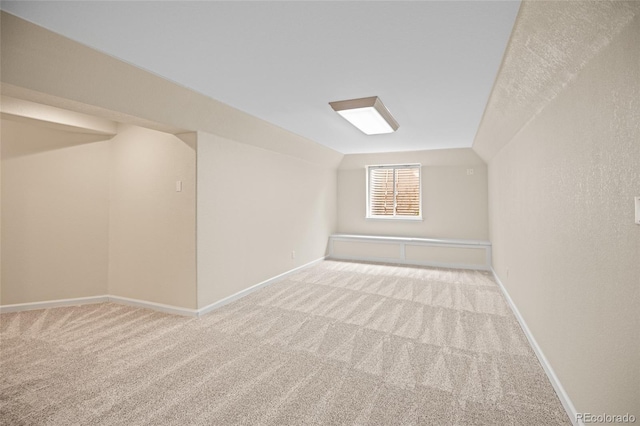 bonus room with vaulted ceiling and light colored carpet