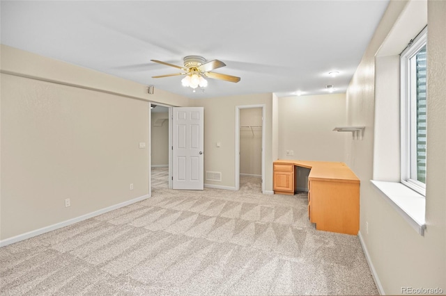 unfurnished bedroom featuring ceiling fan, a walk in closet, multiple windows, and light colored carpet