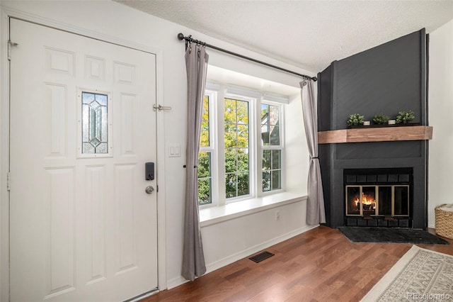 foyer entrance with hardwood / wood-style flooring, a large fireplace, and plenty of natural light