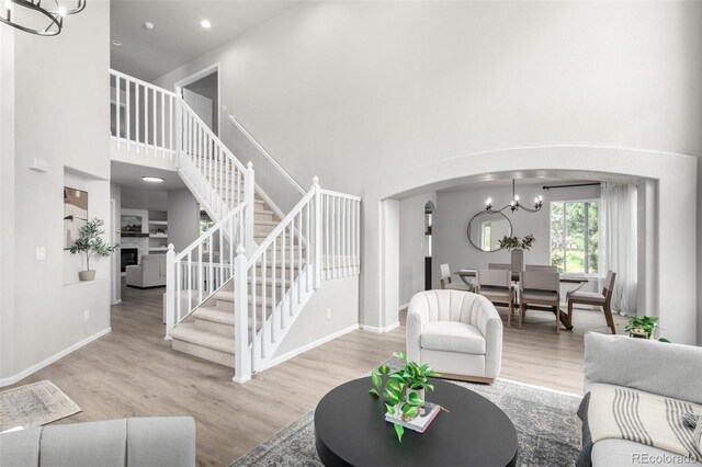 664 Clarendon Dr, Longmont, CO 80504 - living room featuring stairs, arched walkways, wood finished floors, a high ceiling, and a chandelier
