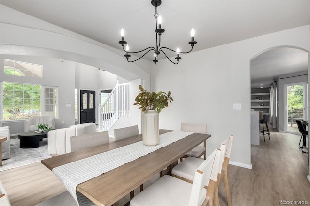 664 Clarendon Dr, Longmont, CO 80504 - dining room with arched walkways, stairs, wood finished floors, and a chandelier