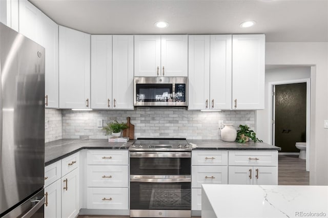 664 Clarendon Dr, Longmont, CO 80504 - kitchen featuring appliances with stainless steel finishes, white cabinetry, dark stone counters, tasteful backsplash, and recessed lighting
