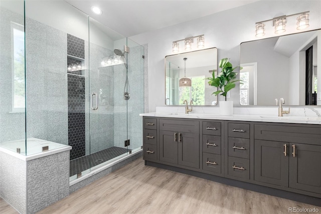 664 Clarendon Dr, Longmont, CO 80504 - bathroom featuring wood finished floors, double vanity, a stall shower, and healthy amount of natural light