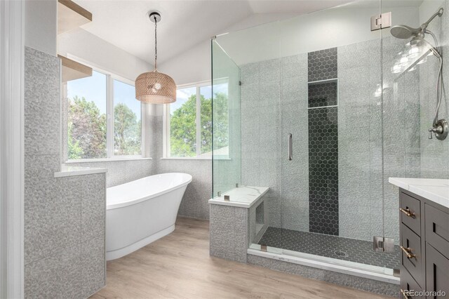 664 Clarendon Dr, Longmont, CO 80504 - bathroom with a shower stall, a soaking tub, wood finished floors, vanity, and tile walls