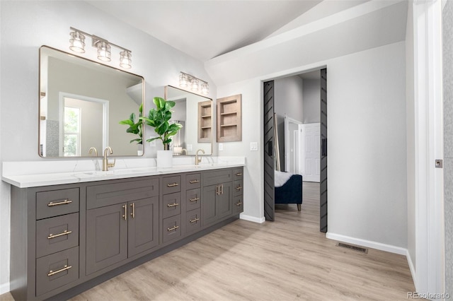 664 Clarendon Dr, Longmont, CO 80504 - full bathroom with double vanity, vaulted ceiling, and wood finished floors