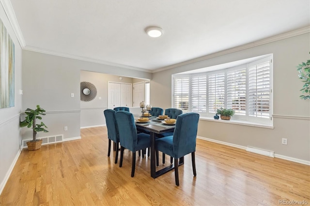 dining room featuring baseboards, visible vents, light wood finished floors, and ornamental molding