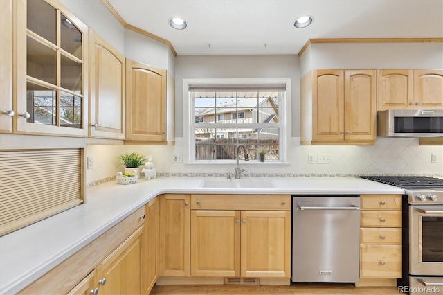 kitchen featuring light brown cabinetry, stainless steel appliances, and a sink