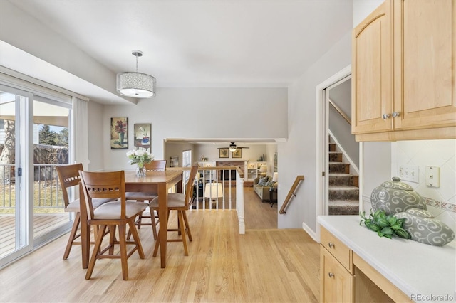 dining area featuring light wood-style flooring, stairs, and ceiling fan