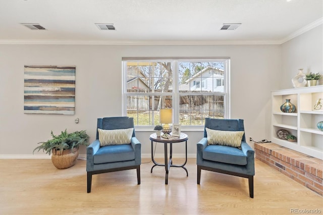 living area with visible vents, ornamental molding, baseboards, and wood finished floors