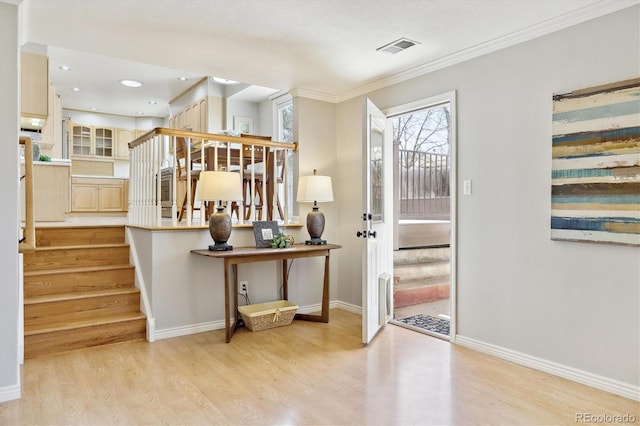 entrance foyer featuring visible vents, stairway, light wood-style floors, crown molding, and baseboards