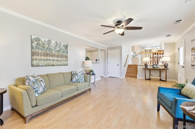 living room with wood finished floors, visible vents, ceiling fan, stairs, and ornamental molding